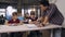 Young Korean teacher standing near schoolchildren who are sitting at the desk in the classroom and explaining something