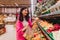 Young Korean woman shopping without plastic bags in grocery store. Vegan zero waste girl choosing fresh fruits and vegetables in