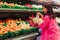 Young Korean woman shopping without plastic bags in grocery store. Vegan zero waste girl choosing fresh fruits and vegetables in