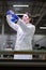 Young lab girl in glasses and white coat with flask with blue liquid in her hands conducts experiments