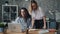 Young ladies colleagues talking looking at laptop screen in office room at desk