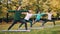 Young ladies yoga students are standing in warrior pose then moving into triangle position during outdoor class in park