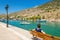 Young lady in blue sitting on bench on wharf of small fishermens