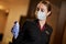 Young lady in corporate uniform using infrared thermometer during pandemic