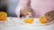 Young lady cutting orange with knife on plate, cooking fresh juice in morning