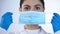 Young lady doctor putting on surgical mask, safety while examining, closeup