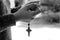 Young lady hand holding rosary beads with Jesus Christ holy cross crucifix on black and white background. Praying The Rosary