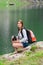 Young lady hiker with backpack sitting on mountain