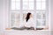 Young lady in leggings and white sweater stretch body while make splits asana on windowsill.