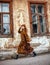 Young lady in long dress on background of an old house on city street, vintage fashion style, rustic antiquity