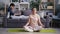 Young lady meditating in lotus position while guy talking on phone using laptop