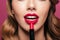 Young lady paint her lips with red lipstick isolated