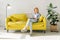 Young lady reading a book on cozy yellow couch