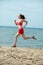 Young lady running at the sunny summer sand beach. Workout. Jog