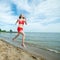 Young lady running at the sunny summer sand beach. Workout. Jog