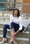 A young lady with short hair,in a white shirt.Dark pants.She sit on the concrete.Holds on to the foot which is very sore.