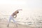 Young lady in sporty top and leggings practicing yoga with amazing sea view on background. Thoughtful woman dreamily