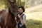 A young lady in a vintage dresses with a long train, lovingly embraces her horse with tenderness and affection. An ancient, collec