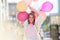 Young lady with violet hair standing in the city street with bunch of baloons