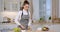 Young lady wearing apron cutting fresh bell pepper and adding it to bowl, cooking vegetable salad at kitchen