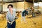 Young latin-american female farmer cleaning goat shed