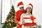 Young latin couple smiling happy and hugging unboxing christmas gift at home