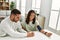 Young latin couple smiling happy measuring blood pressure using tensiometer at home