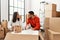 Young latin couple smiling happy unboxing cardboard box at new home