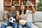 Young latin couple watching soccer match eating porpcorn at home