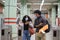 Young latin couple wearing protective face mask walking through subway turnstile at the train or metro station