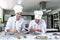 Young latin couple woman and man chocolatier in chef uniform and hat preparing mexican chocolates bonbon candies at kitchen in Mex