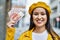 Young latin girl smiling happy holding norway krone banknotes at the city