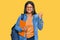 Young latin girl wearing student backpack and holding books very happy and excited doing winner gesture with arms raised, smiling