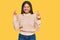 Young latin girl wearing wool winter sweater gesturing finger crossed smiling with hope and eyes closed