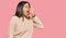 Young latin girl wearing wool winter sweater shouting and screaming loud to side with hand on mouth