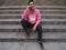 Young latin handsome man sitting on the stairs, talking on the phone and looking up