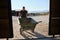 Young latin man carrying a wheelbarrow to pick up horse excrements in stall.