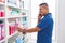 Young latin man customer smiling confident talking on smartphone at pharmacy