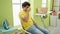 Young latin man drinking coffee waiting for washing machine at laundry room