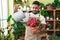 Young latin man florist watering plant at flower shop