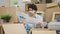 Young latin man reading document sitting on floor looking upset at new home