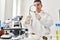 Young latin man scientist looking cannabis herb with loupe at laboratory