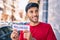 Young latin man smiling happy holding wellness word paper standing at the city