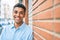 Young latin man smiling happy leaning on the wall at the city