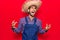 Young latin man wearing farmer hat and apron crazy and mad shouting and yelling with aggressive expression and arms raised