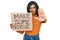 Young latin transsexual transgender woman holding make some noise banner with open hand doing stop sign with serious and confident