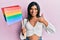 Young latin transsexual transgender woman holding rainbow lgbt flag smiling happy and positive, thumb up doing excellent and