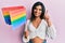 Young latin transsexual transgender woman holding rainbow lgbt flag smiling with an idea or question pointing finger with happy