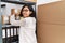 Young latin woman ecommerce business worker organizing packages shelving at office