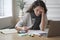 Young latin woman office worker sitting at table with digital thermometer in hand